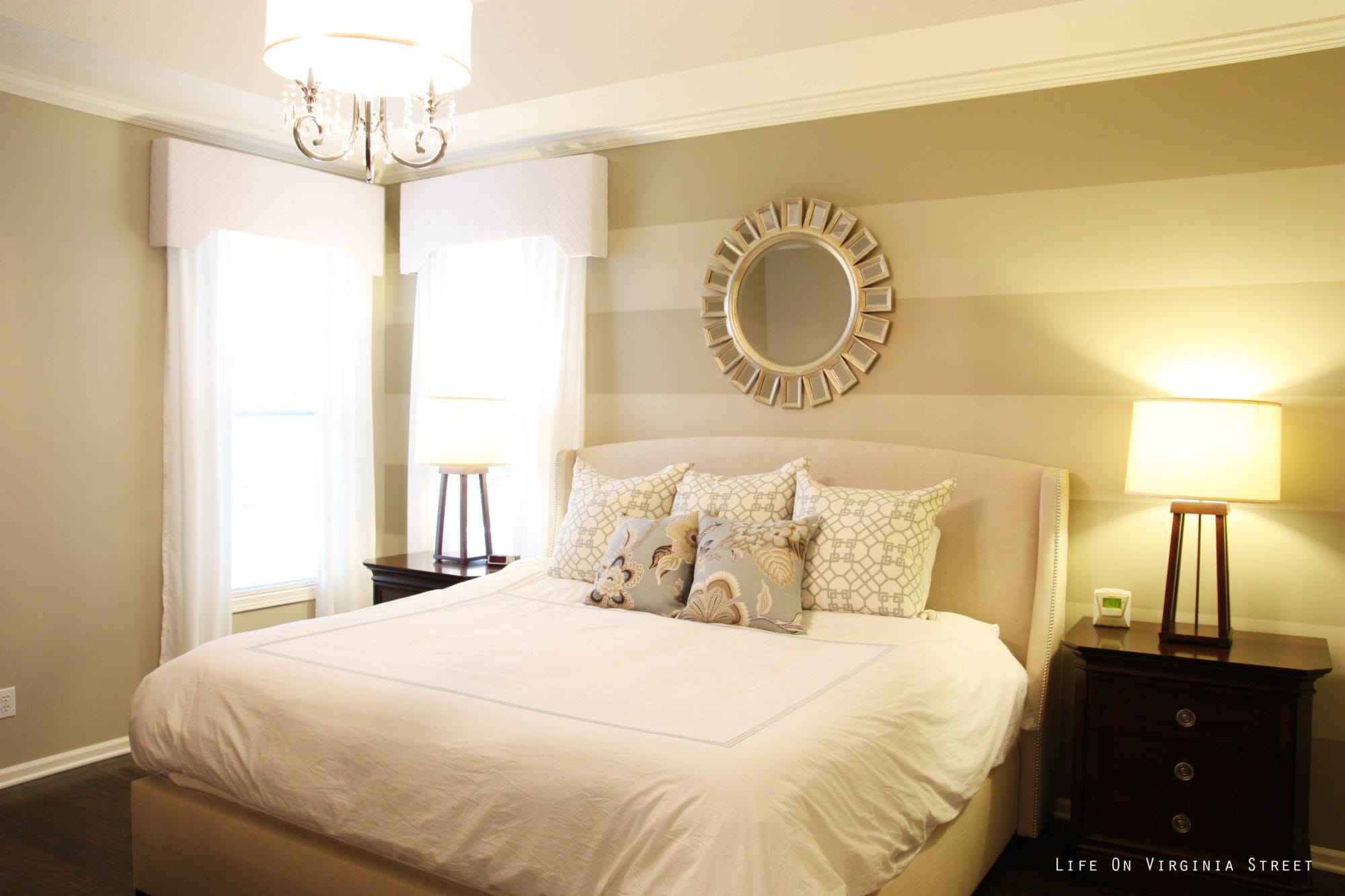 The master bedroom with striped walls, and a round mirror above the bed.