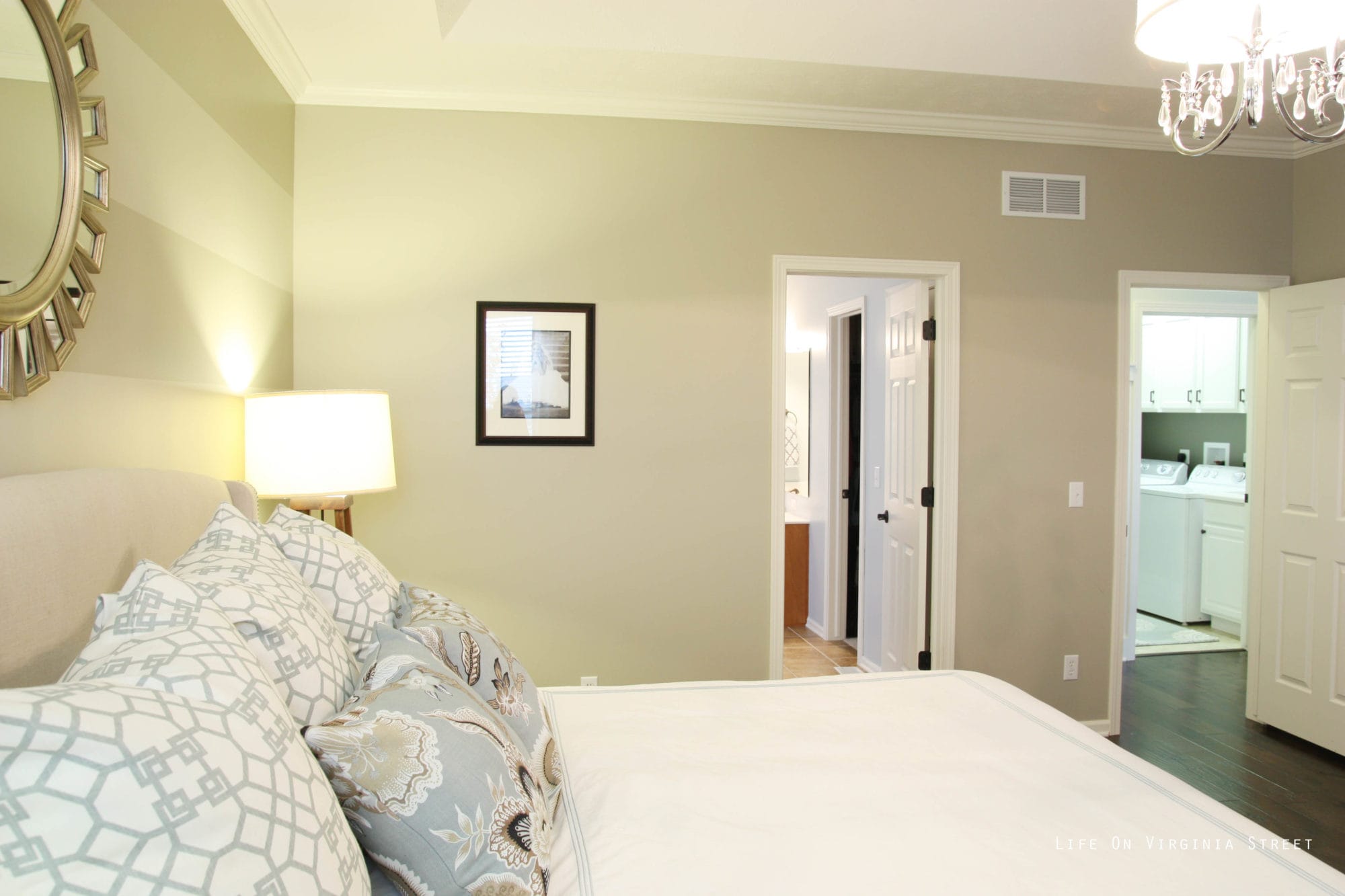 White bedding in the master bedroom with light blue and white pillows.