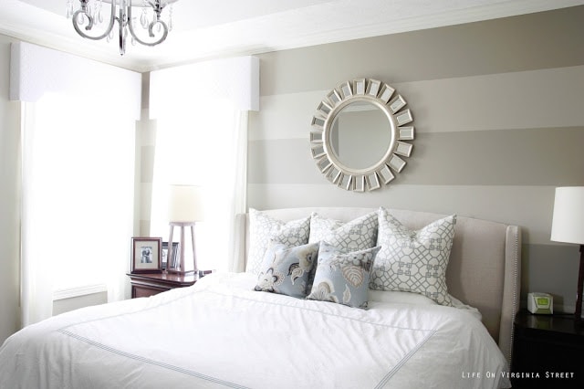 Striped Master Bedroom Wall with White Bedding and a round mirror above the bed.