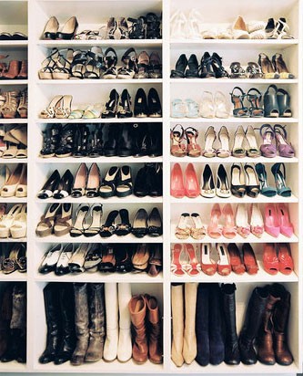 Shoe closet with built in shelves and shoes and boots on the shelves.