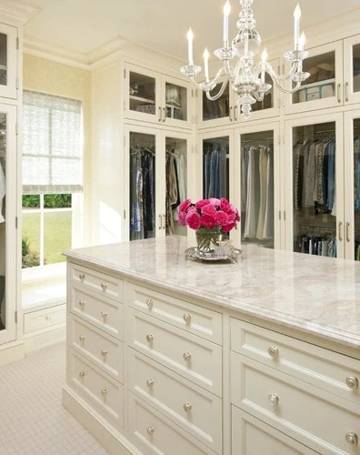 Closet with marble island and chandelier.