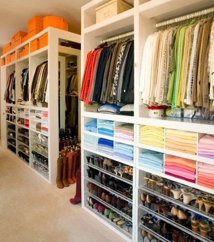A walk in closet with multiple shelves, and shoes and boxes.