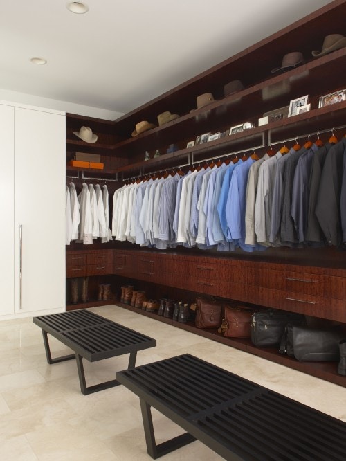 A dark wood closet with mens clothes.