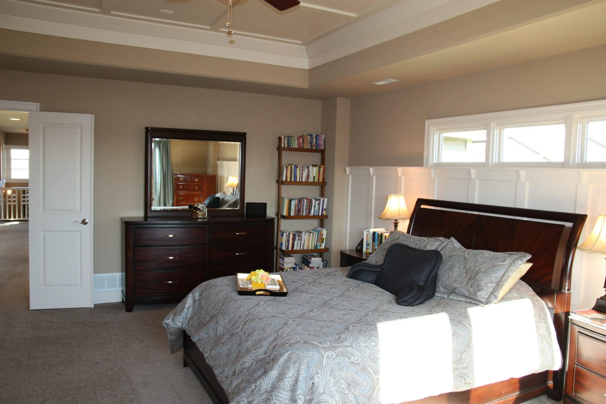 A large bedroom with a dark wood bed, dresser and door opened to the hallway.