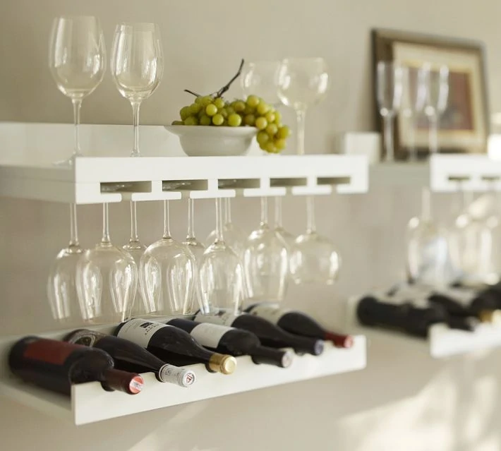 Wine bottles on shelves, green grapes, and clear wine glasses on shelves.
