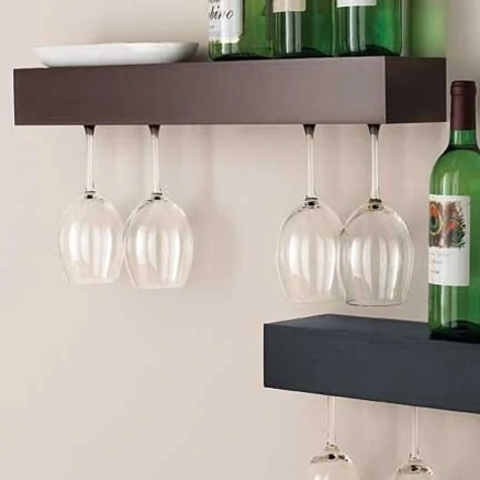 Modern wooden shelves on the wall holding wine glasses and wine bottles.