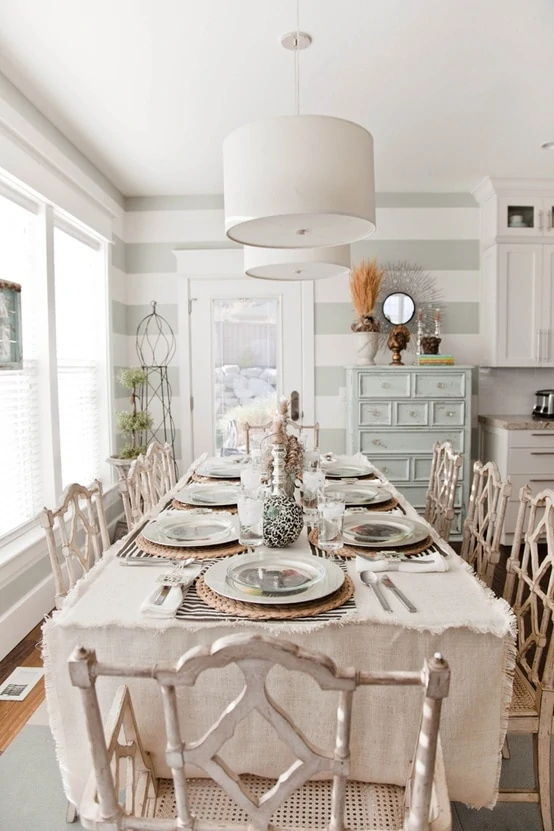 A large set dining room table with a striped wall at the foot of the table.