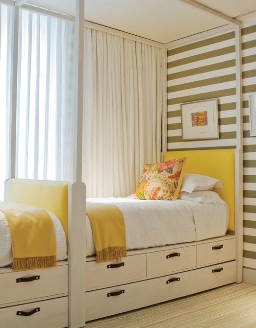 A white canopy bed with a green and white striped wall in the room.