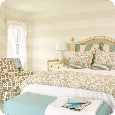 A bedroom with light blue touches and a very light white and off white striped wall.