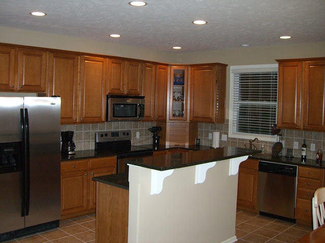 White Island with black top and maple cabinets in kitchen.