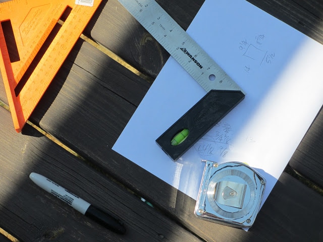 Measuring tape and angled ruler on white paper with measurements on it.
