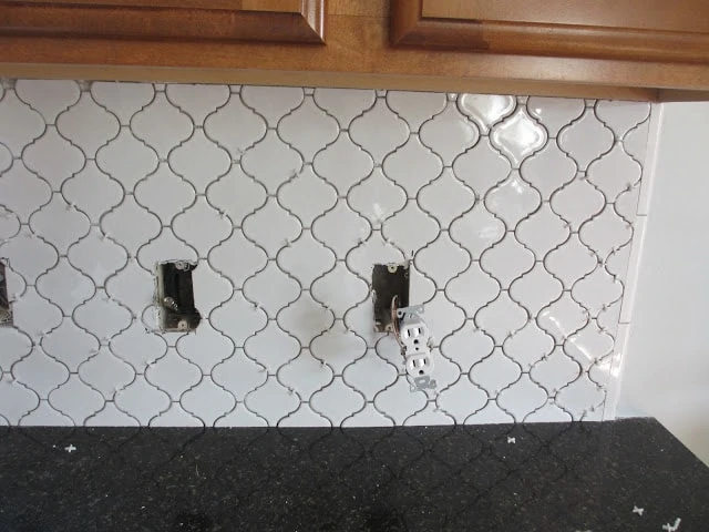 White Moroccan Tile backsplash ungrouted on the wall with electrical sockets hanging out.