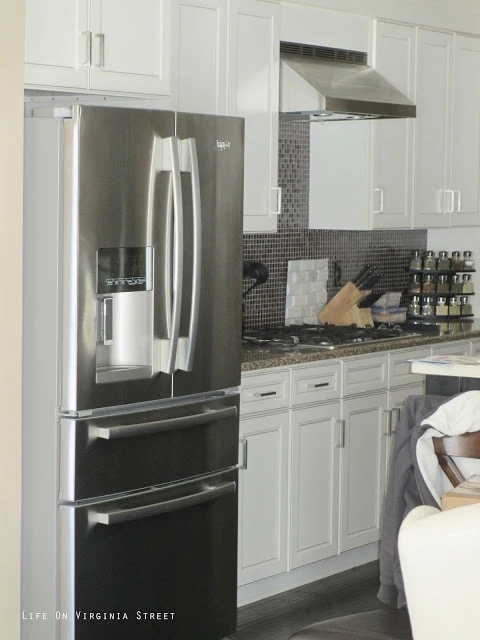 Stainless steel fridge and white cabinets in the kitchen.