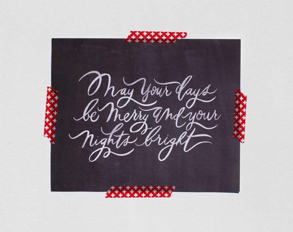 Black background with white handwritten print and red tape on the wall.
