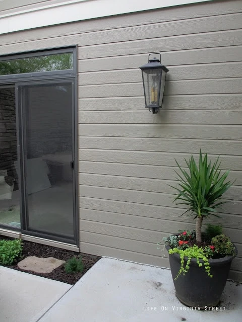 A light fixture and a planter on the side of the house.