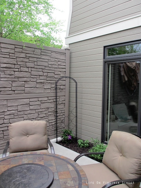 A small garden area in the corner of the courtyard with purple flowers.