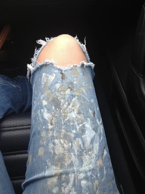 Jeans with a rip in the knees and paint all over the jeans.