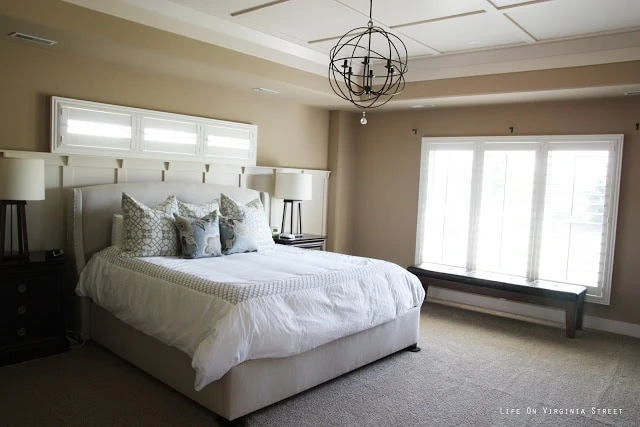 Master bedroom with white plantation shutters and orb chandelier.