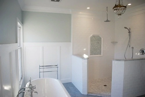 White bathroom with gray green walls and claw foot tub, and chandelier.