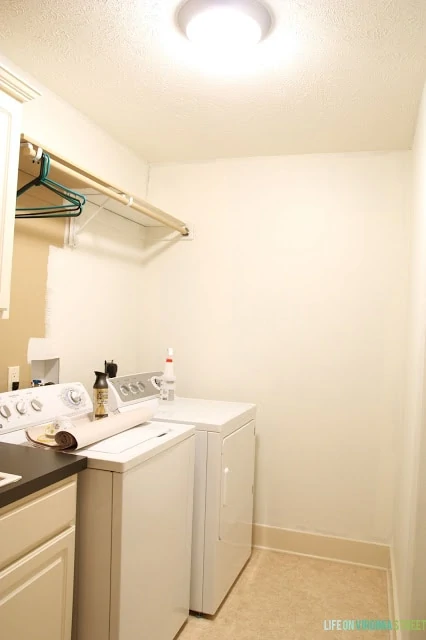 The white walls, washer and dryer, and brown countertops in laundry room.