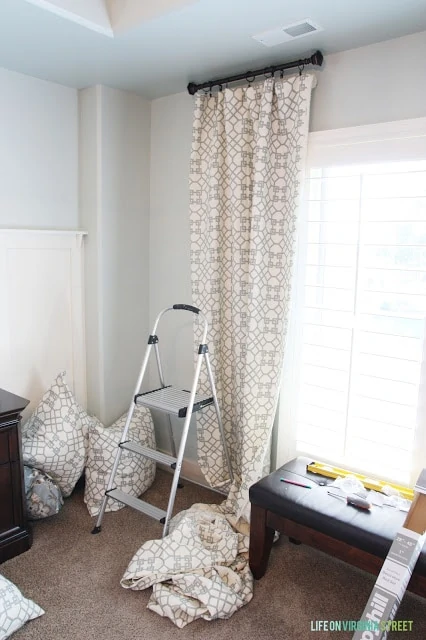 Putting up the curtains with a stepladder.