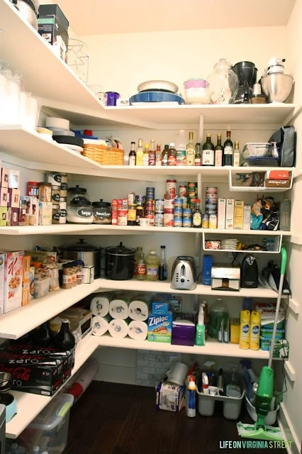 Organized pantry with food and mixing bowls and a swiffer.
