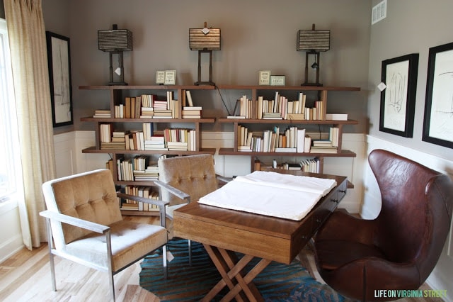 A wooden desk, leather chair and fabric chairs in a neutral office.