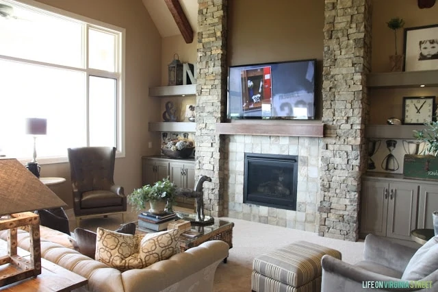 Living room with stone fireplace wall surrounded by gray built-in cabinets and shelving.