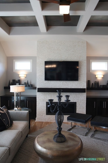 A neutral living room with a gray couch and an electric fireplace.