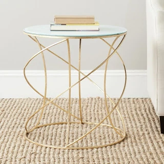 A gold and glass side table with books on it.