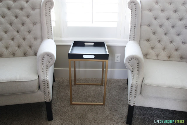 A gold legged side table with a black tray top.