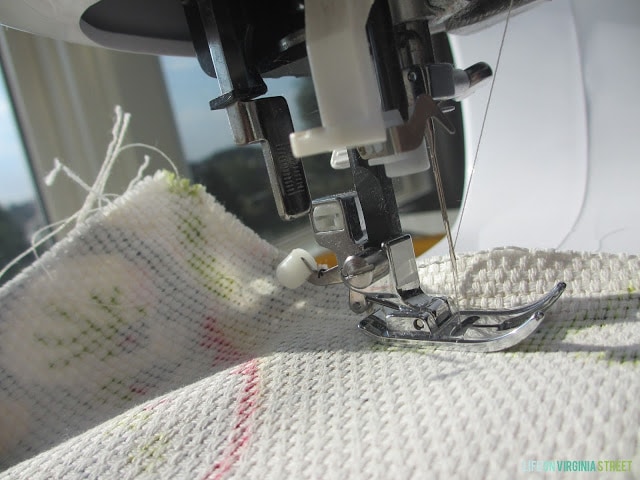 The foot of the sewing machine on the fabric.