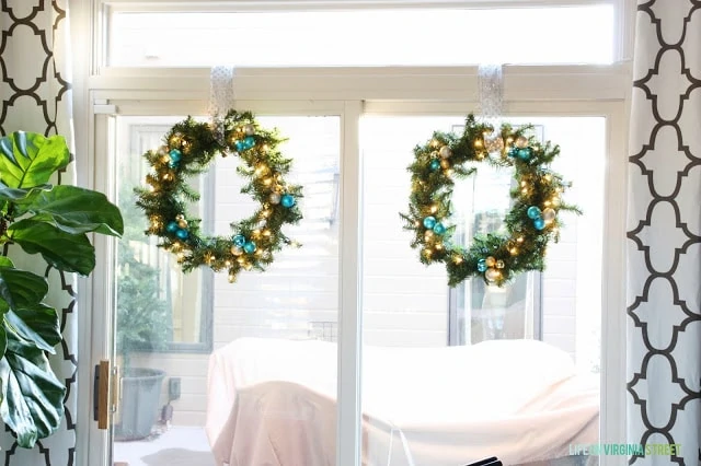 The two Christmas wreaths on the window with the pretty ornaments on them.
