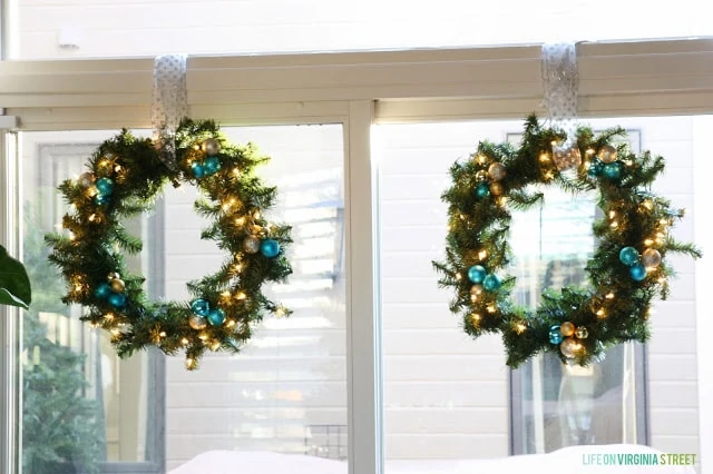 White window sill and blue and gold sparkly wreath hanging by ribbon.