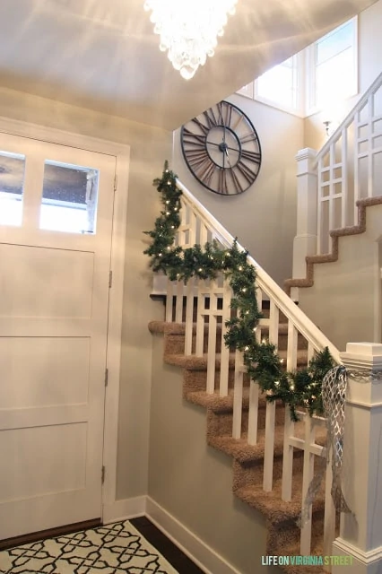 The stairs in the entryway with garland on the railing.