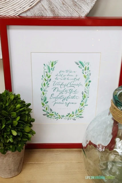 A red picture frame has a Christmas quote inside it.