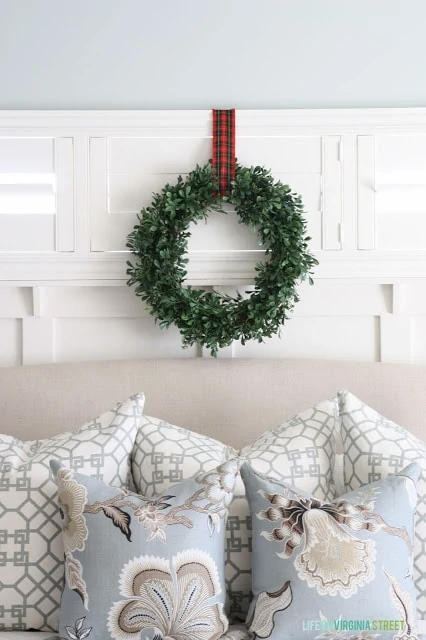The green wreath with a plaid ribbon above the bed.