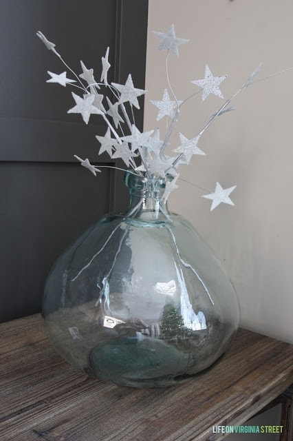 Glittery stars are in the clear glass vase.