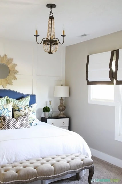 Guest Bedroom with blue headboard, board and batten walls and ribbon-trimmed roman shades