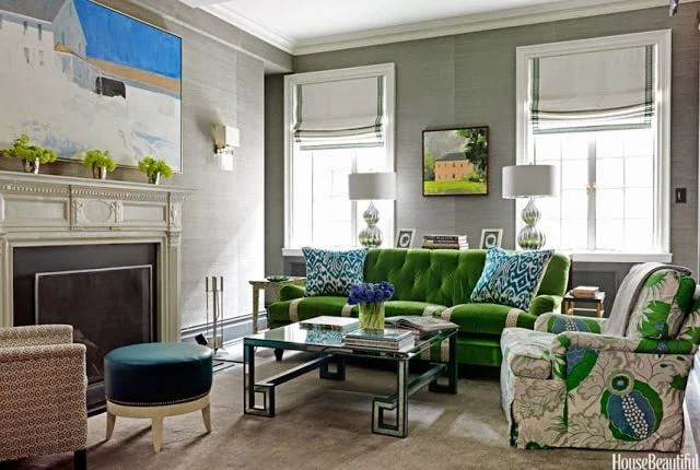 Emerald green couch and floral armchair in living room by the fireplace.