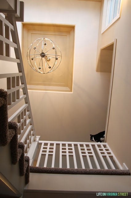 A black and white cat is walking on the bannister.