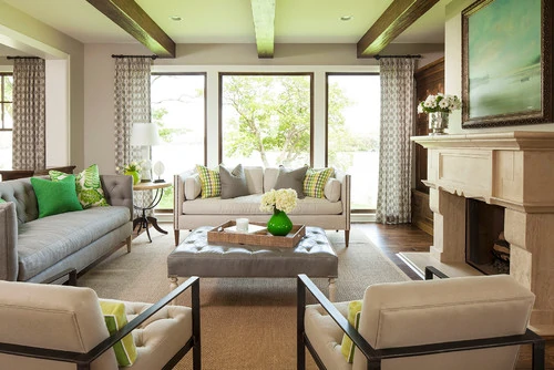 Neutral living room with green pillows and green glass on coffee table.