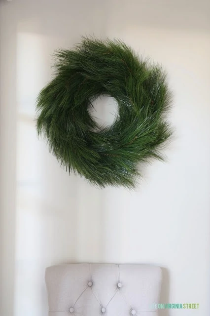 Large green wreath hanging on white wall.