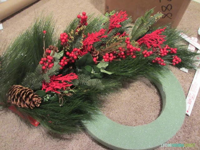 Wreath material with pine cones and red berries.