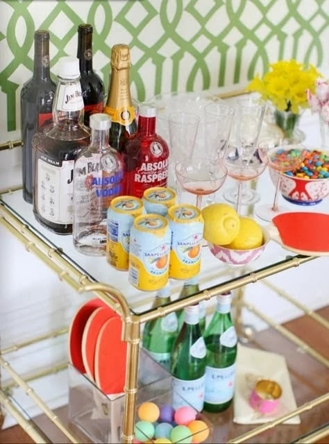 Vodka, candies and yellow flowers on bar cart.