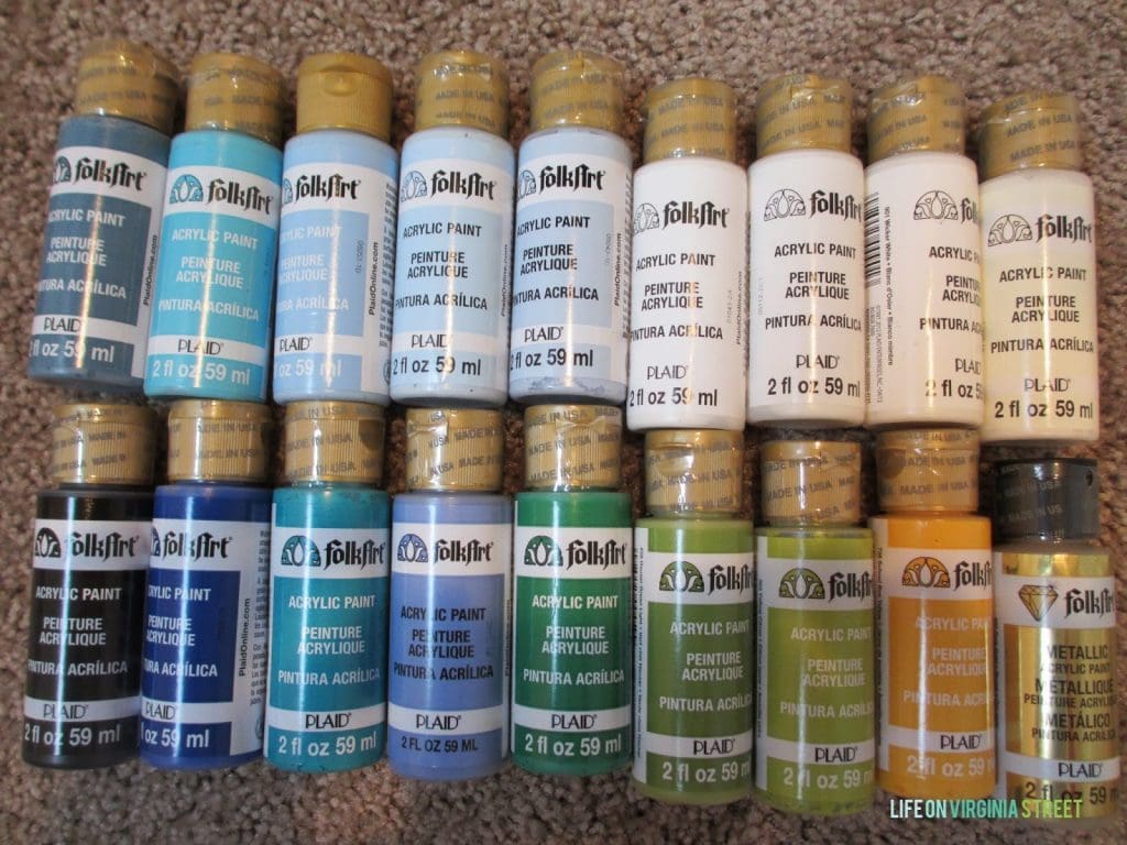 Two rows of acrylic paint laid out on the counter, in various colors.