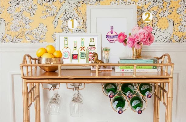 A gold bar cart with pink flowers and lemons on the bar.