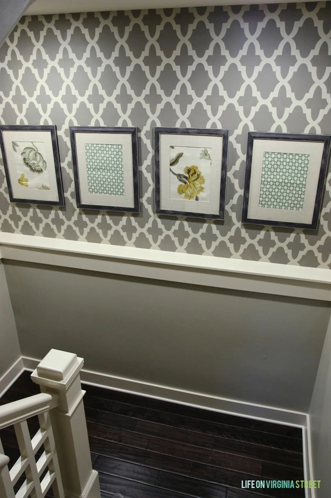 A staircase that has been stencilled with pictures hanging on the wall.