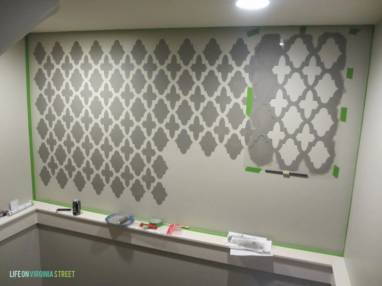 Painting the stencils on the wall in a grey color.