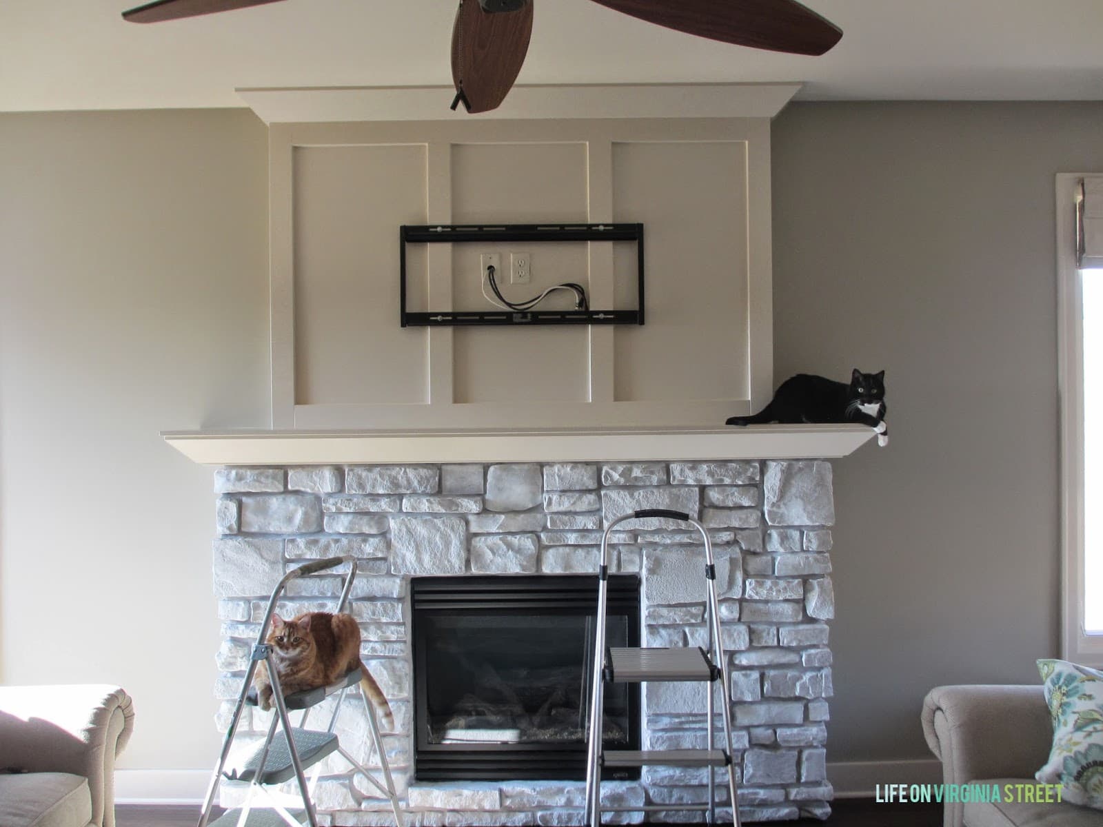 The fireplace being painted with the cats sitting on the top of the fireplace and also the step stool.